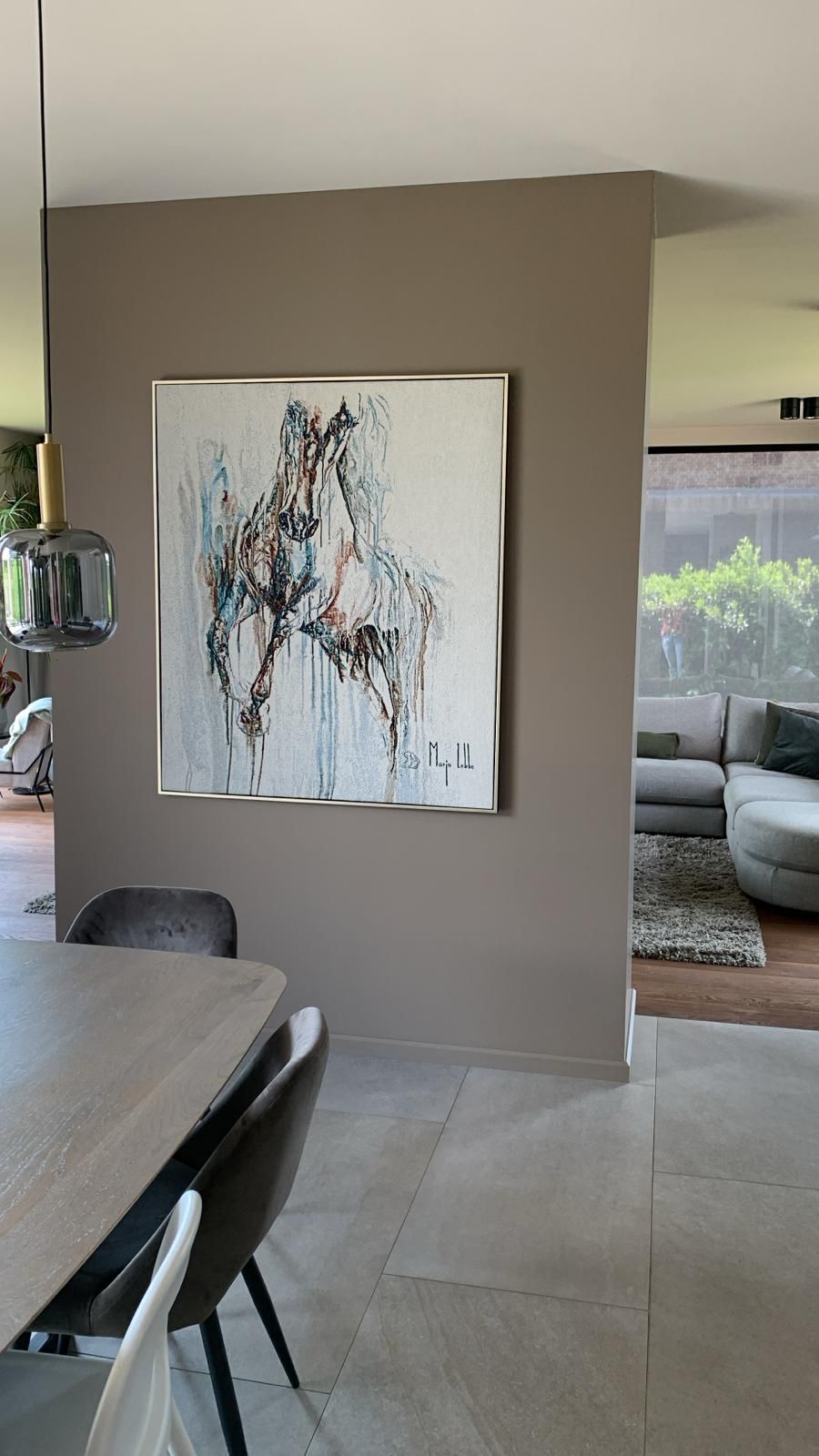 Expressive horse painting on a taupe wall in a modern open-plan home