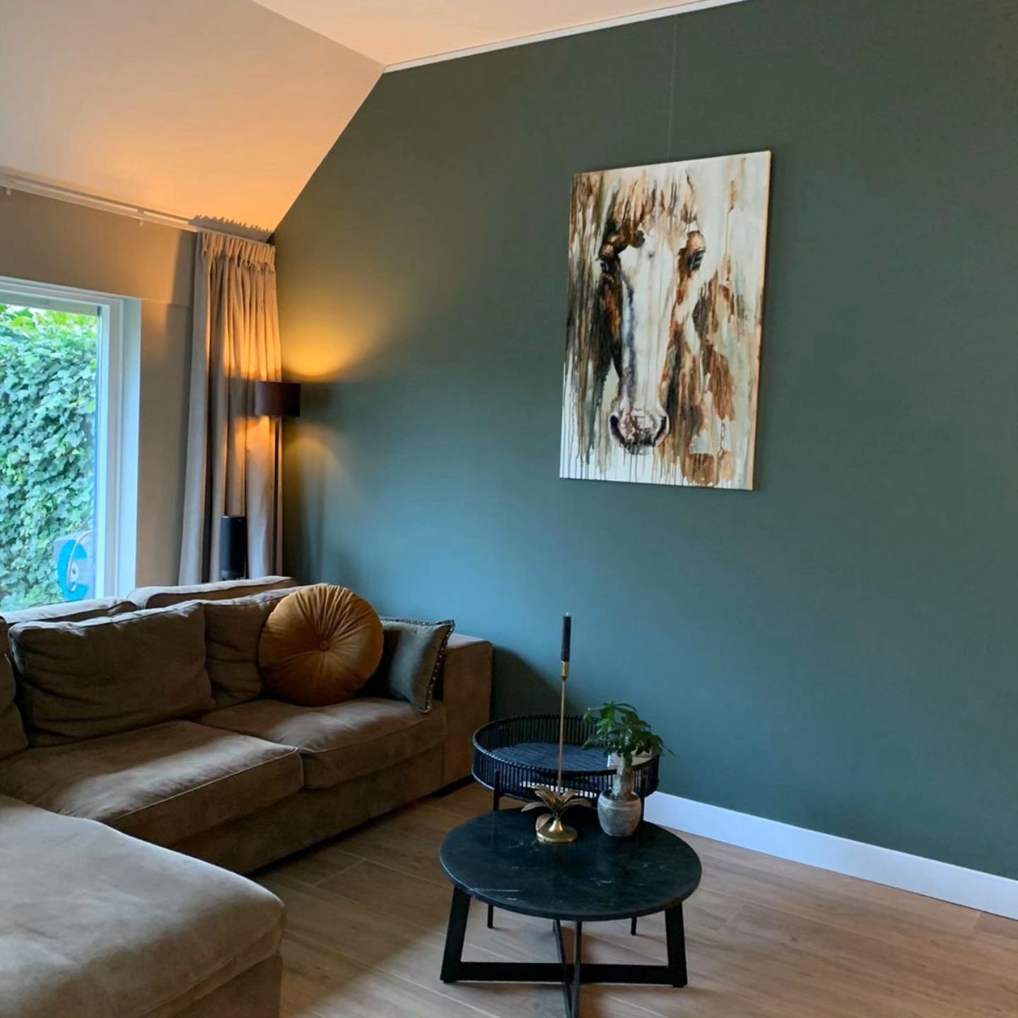 James, horse portrait hanging on a deep green wall above a velvet sofa