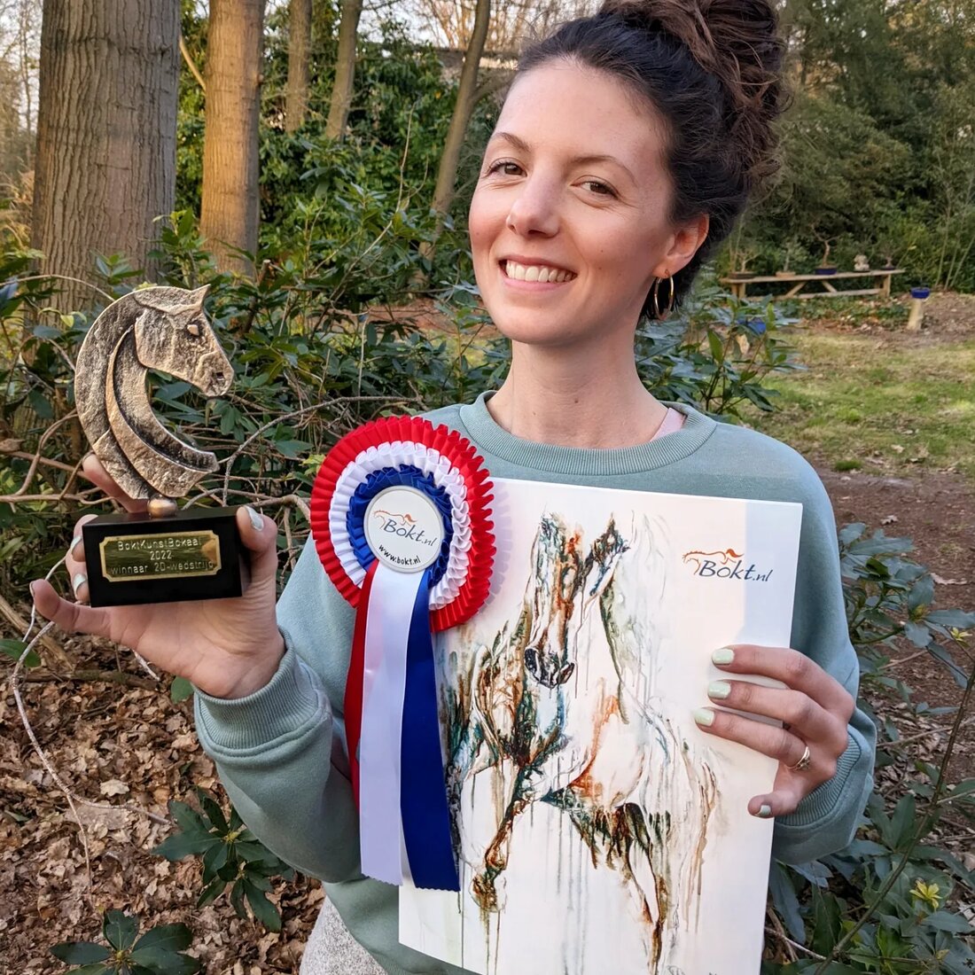 Marjo Lebbe holding the BoktKunstBokaal 2022 and her winning painting Footloose