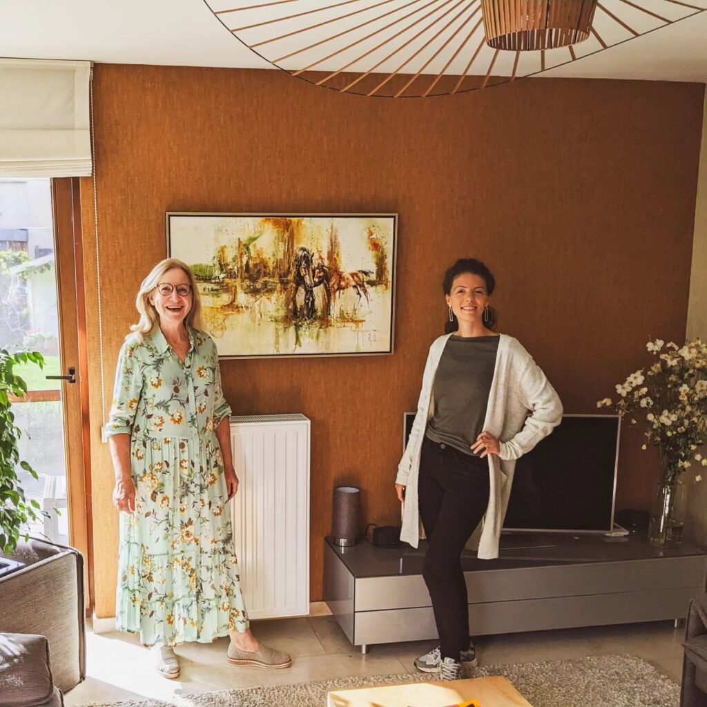 A wide horse painting on a living-room wall with two people beside it for scale