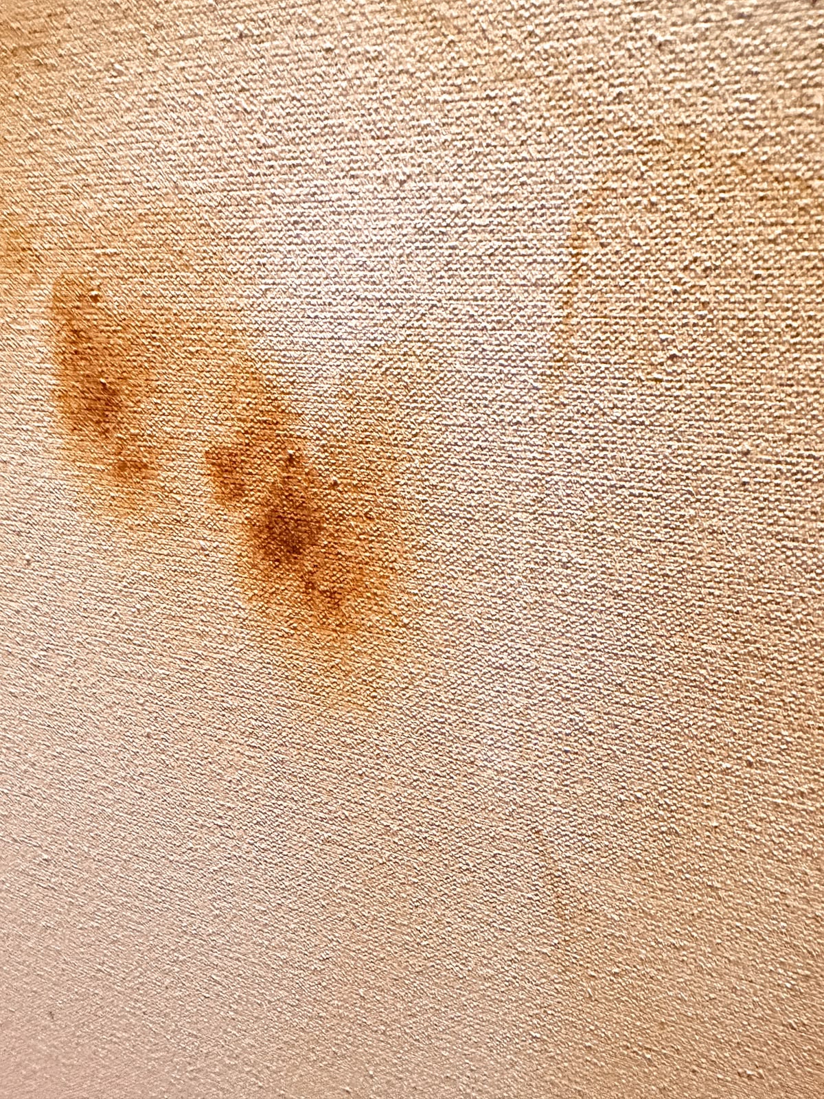 Detail van roestkleurige inktvlekken op het blanke linnen weefsel