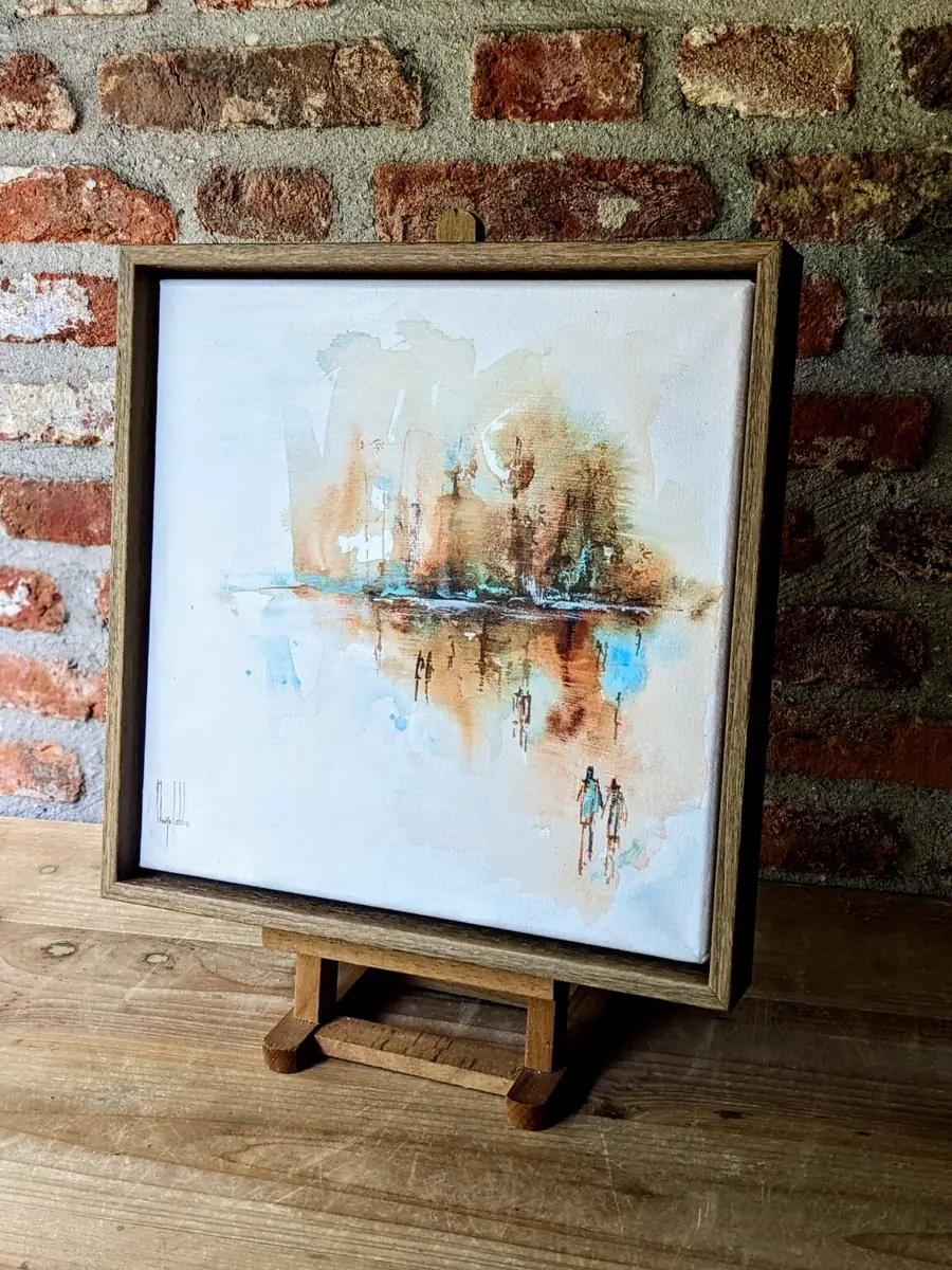 The painting on a wooden easel against a brick wall, seen from an angle so the depth of the floating frame shows