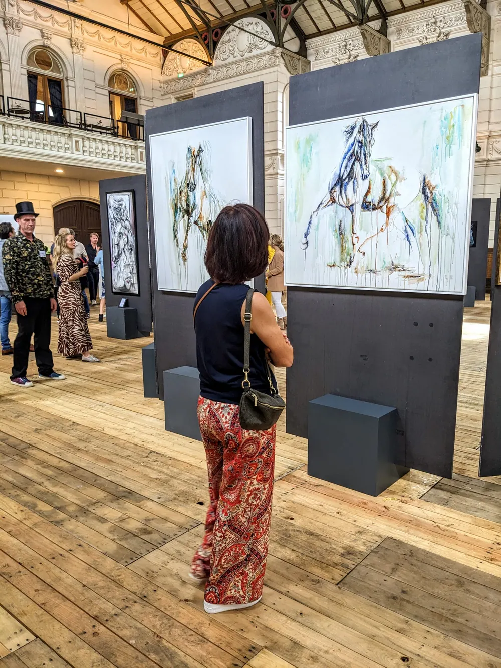 A visitor standing in front of Elusive, hung on a dark exhibition panel in a light-filled hall