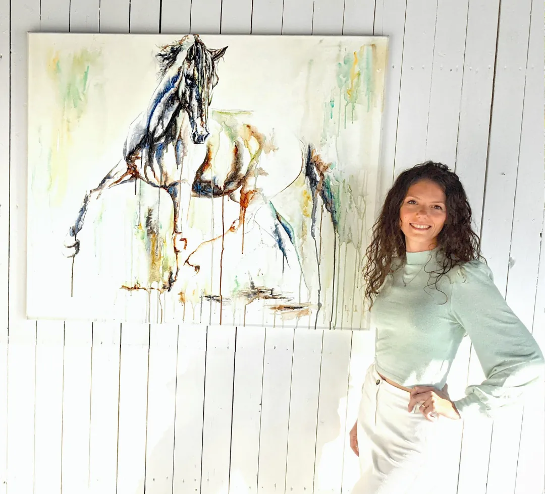 Marjo Lebbe standing beside Elusive, the unframed canvas hanging on a white plank wall in daylight