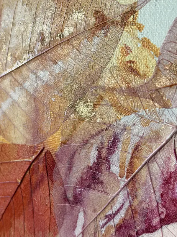 Detail of the wide work: gold leaf and translucent skeleton leaves catching low light on the linen canvas