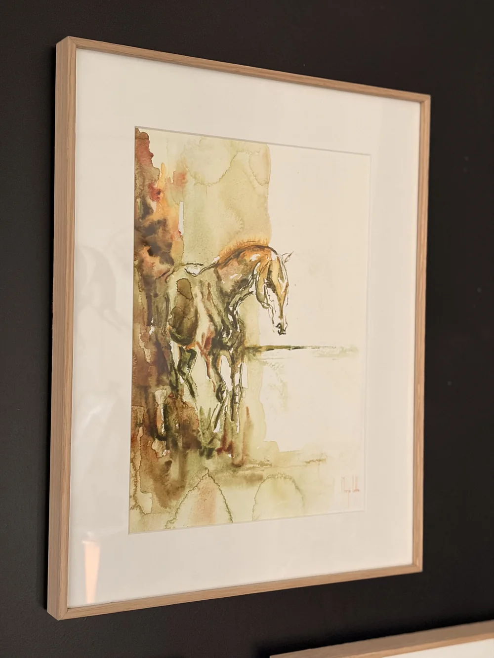 A framed Praise watercolour hanging on a wall, seen at an angle