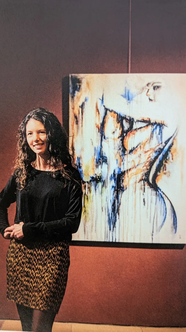 Serendipity hung on a deep red wall, Marjo standing in front of it