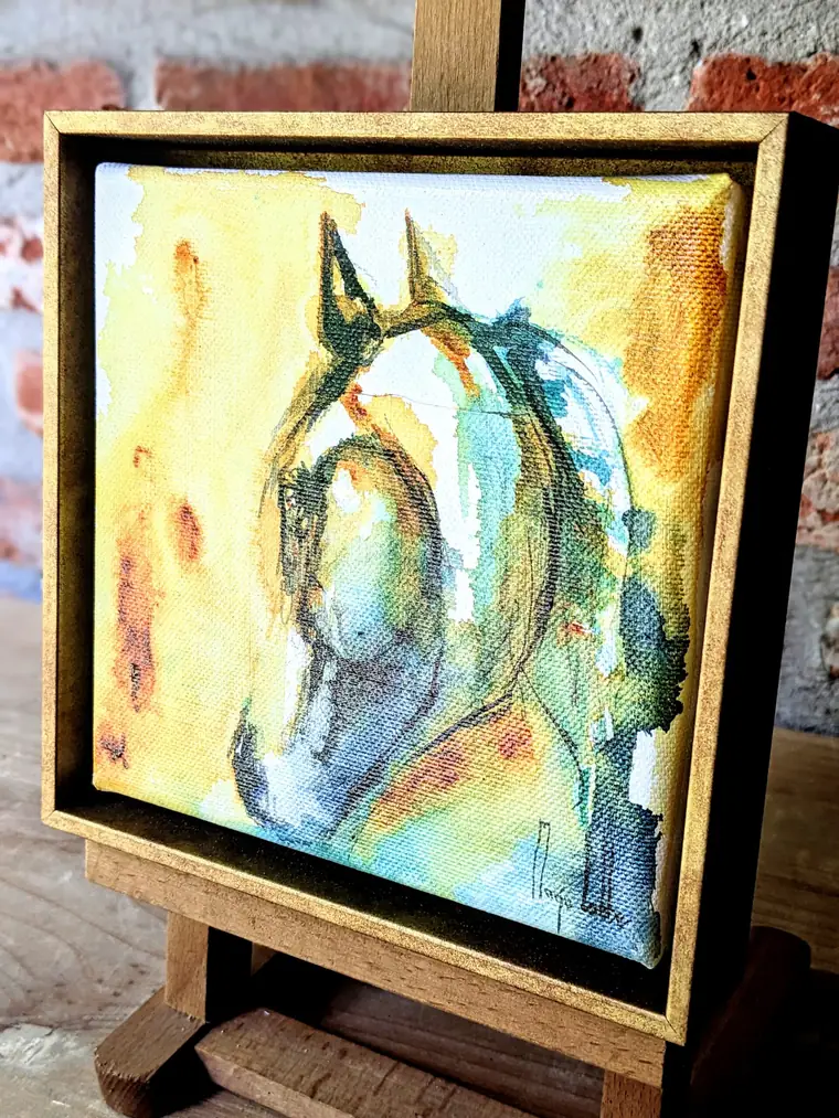 Het gele en turkooizen paardenhoofd op een ezeltje tegen een bakstenen muur, van opzij gezien