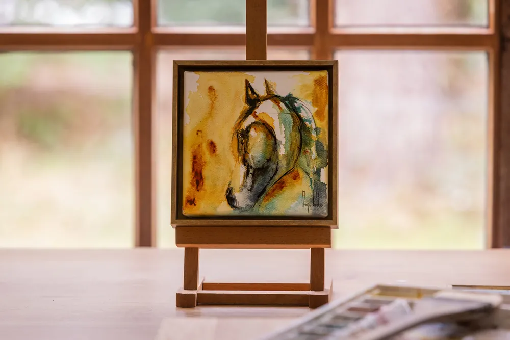Het gele en turkooizen paardenhoofd op een klein houten ezeltje bij een atelierraam